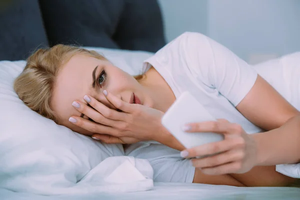 Стресова Жінка Лежить Ліжку Дивлячись Камеру Покриваючи Обличчя Рукою Використовуючи — стокове фото