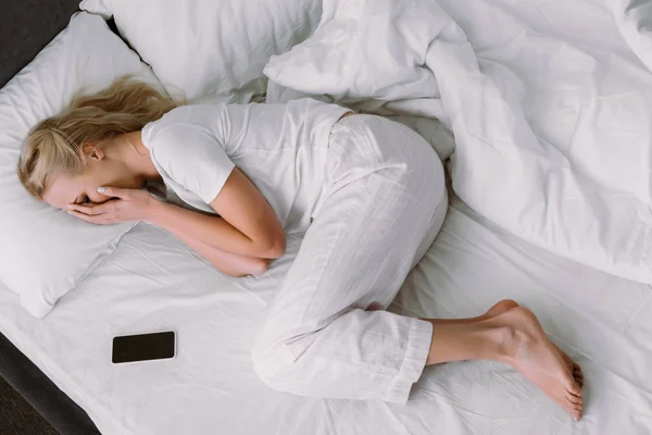 Mujer Cubriendo Cara Llorando Mientras Está Acostado Cerca Teléfono Inteligente — Foto de Stock