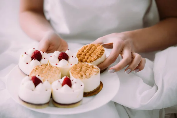 Cropped View Woman Holding One Cakes Plate Bed — Stock Photo, Image