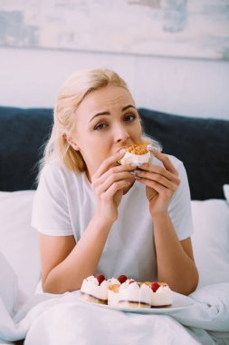 kameraya bakarak ve yatakta yalnız pasta yemeye pijama kadın