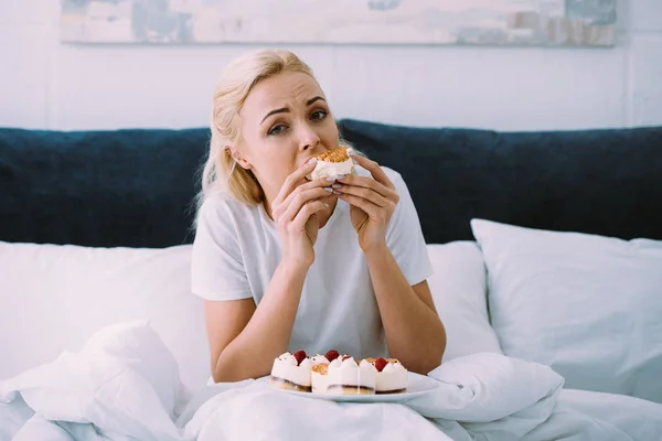 Upset Woman Pajamas Looking Camera While Eating Cake Bed Alone — Stock Photo, Image