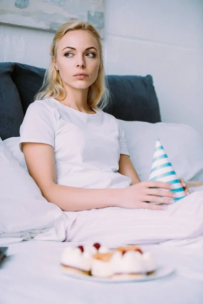 Uspet Woman Holding Party Hat While Celebrating Birthday Bed Alone — Stock Photo, Image