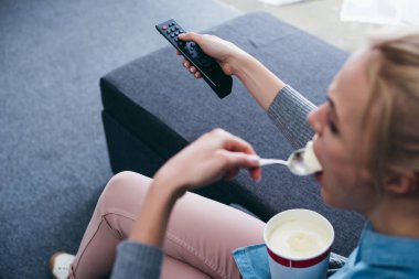 kanepede oturan ve tv izlerken dondurma yemek kadın görünümünü kırpılmış