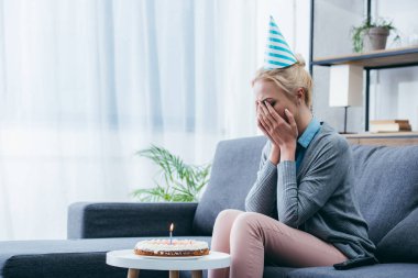tek başına evde Doğum günü kutlamaları sırasında ağlıyor parti şapkalı kadın üzgün