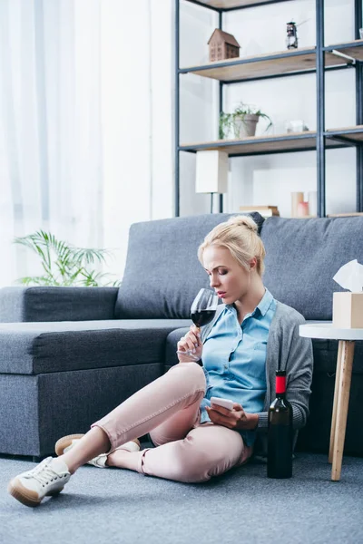 Sorgliga Kvinna Hålla Glas Vin Och Använda Smartphone Hemma — Stockfoto