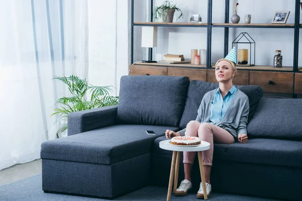 Frustrierte Frau Mit Partyhut Sitzt Auf Couch Und Feiert Geburtstag — Stockfoto