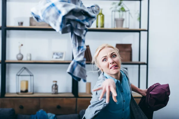 積極的な女性が彼氏と別れた後の居間で服を投げる — ストック写真