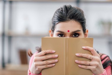 bindi yüzü önünde kitap ile Hint öğrenci