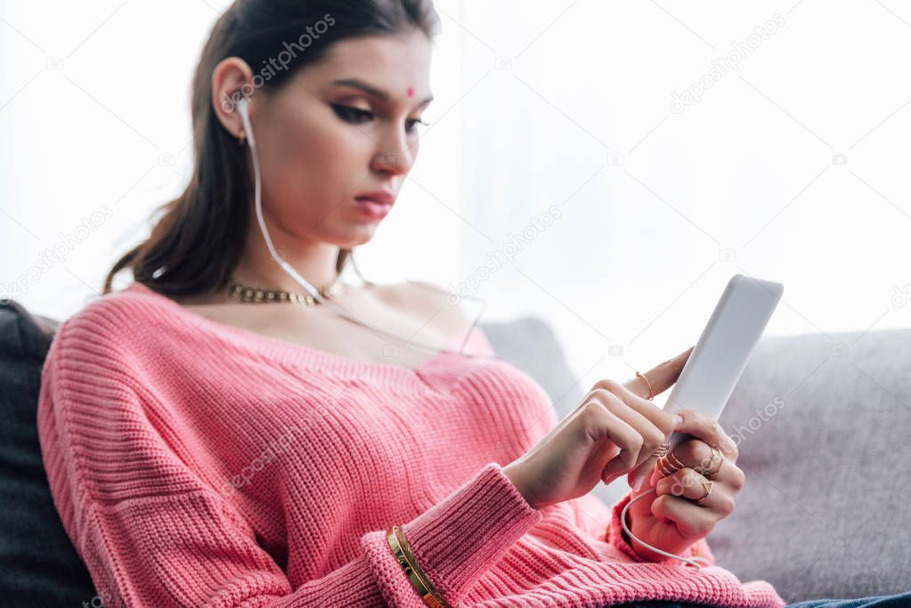 attractive indian woman listening music with earphones and smartphone