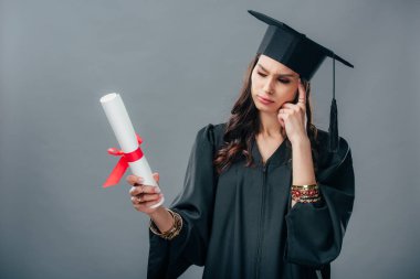 diploma, gri izole bakarak akademik elbisesi ve mezuniyet şapkalı düşünceli Hint öğrenci