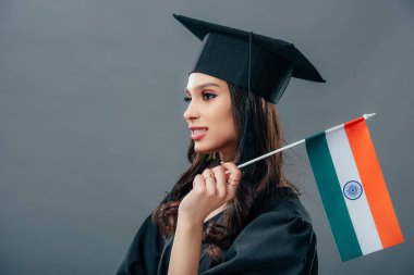 indian student in academic gown and graduation cap standing with indian flag, isolated on grey clipart