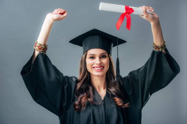 Kız Hint öğrencinin akademik elbisesi ve mezuniyet şapkalı gri izole diploması ile kutluyor
