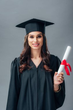 Kız Hint öğrencinin akademik elbisesi ve mezuniyet şapka diploma tutan gülümseyerek, gri izole