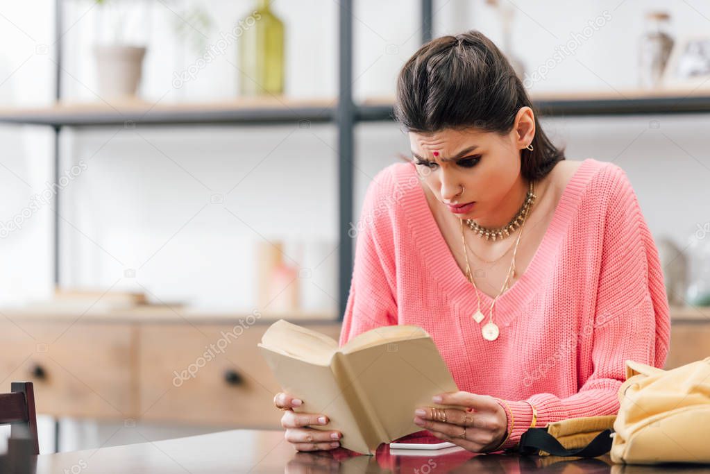 indian woman with bindi studying at home and reading book