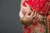 abgeschnittene Ansicht einer indischen Frau, die in traditioneller Kleidung und Accessoires posiert, isoliert auf grau 
