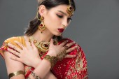 elegante Indianerin posiert in traditionellem Sari und Accessoires, isoliert auf grau 