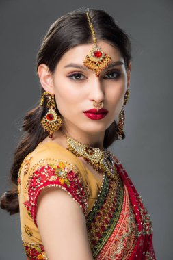 gülümseyen Hintli kadın geleneksel sari ve bindi poz, gri izole 