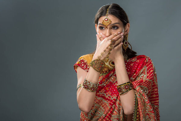 beautiful indian woman closing mouth with hands, isolated on grey 