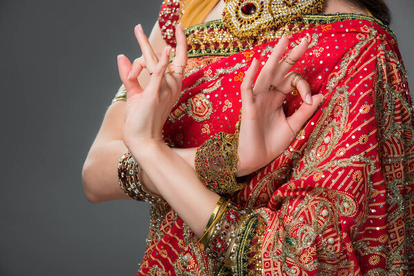cropped view of indian woman in traditional clothing showing gyan mudra, isolated on grey 