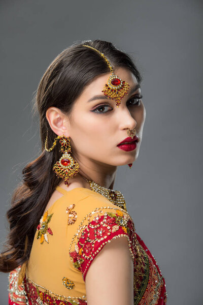 beautiful indian woman posing in traditional sari and accessories, isolated on grey 
