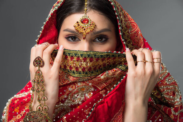 beautiful indian woman with bindi closing face, isolated on grey 