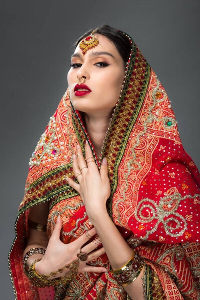elegant indian woman posing in traditional sari and accessories, isolated on grey 