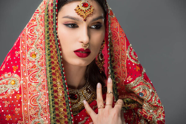 attractive indian woman posing in traditional sari and accessories, isolated on grey 