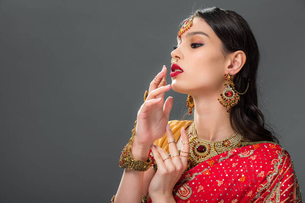 attractive indian woman gesturing in accessories, isolated on grey 