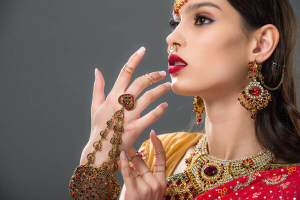 indian woman in traditional sari and accessories gesturing isolated on grey 
