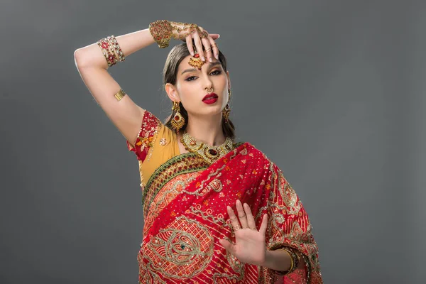 indian woman gesturing in sari and accessories, isolated on grey