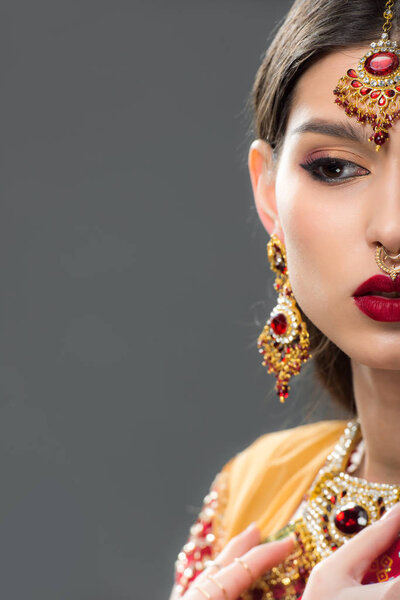 half view of attractive indian woman in sari and accessories, isolated on grey 