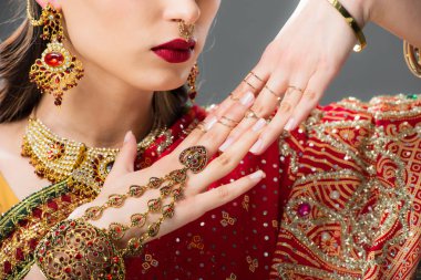 cropped view of attractive indian woman gesturing in traditional accessories, isolated on grey  clipart