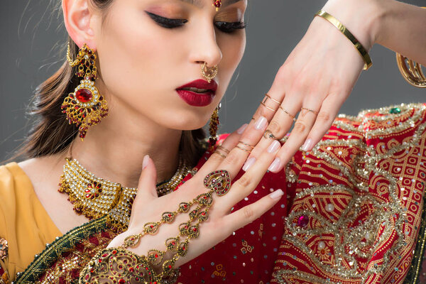 beautiful indian woman in sari and accessories on hands, isolated on grey 