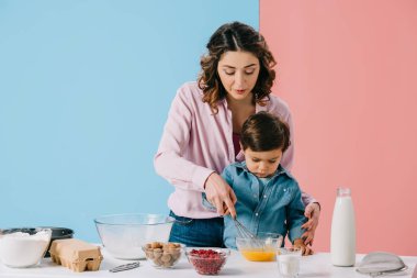 sevimli küçük oğlu kasede yumurta bicolor arka plan üzerinde birlikte kırbaçlanan ile güzel anne