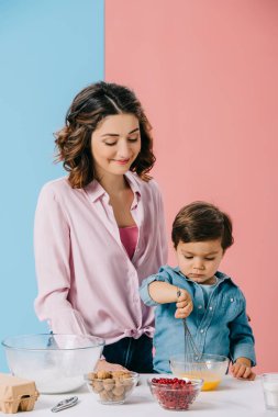 sevimli küçük çocuk yumurta mutlu anne gülümseyerek bicolor arka plan üzerinde bicolor arka plan üzerinde gözü üstünde iken kırbaçlanan 