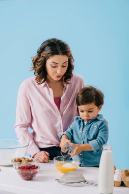 şeker için ekleyerek şirin küçük çocuk anne onu mavi izole bakarak süre yumurta şanti