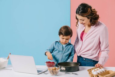 sevimli küçük çocuk annesi bicolor arka plan üzerinde ile pişirme sırasında form pişirme için kızılcık ekleme 