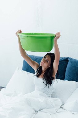 Upset woman using basin during leak in bedroom clipart