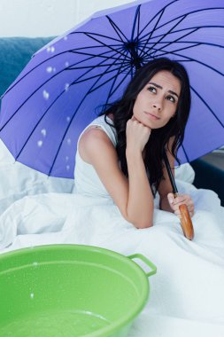 Su tavandan yatak odasında sızıntı bakarak şemsiye ile üzgün kız