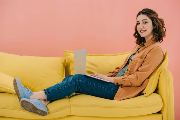 有吸引力的女人坐在黄色沙发上 并使用笔记本电脑 — 图库照片
