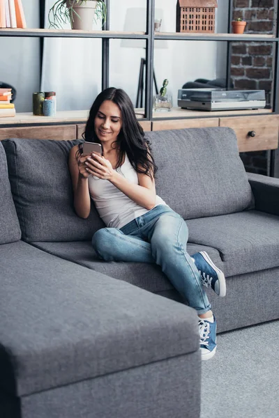 Mujer Morena Sonriente Con Teléfono Inteligente Sentado Sofá — Foto de Stock