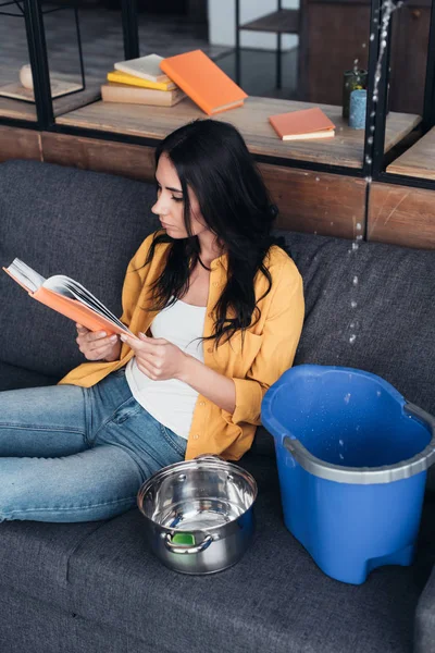 Konzentrierte Frau Liest Buch Bei Wasserschaden Wohnzimmer — Stockfoto