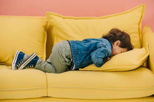 Cute little boy lying face down on comfortable yellow sofa — Stock Image Cute Little Boy Lying Face Comfortable Yellow Sofa Stock Photo