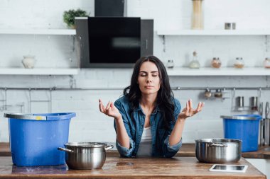 Woman trying to calm down during water damage in kitchen clipart