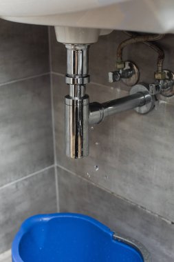 Mavi kova ayakta boru sızıntı altında banyoda