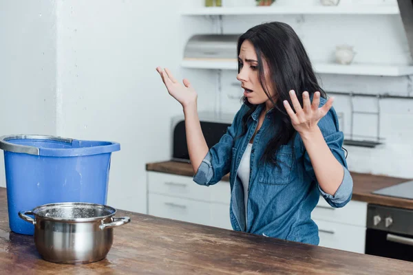 Mulher Triste Com Panela Balde Acenando Mãos Durante Vazamento Cozinha — Fotografia de Stock