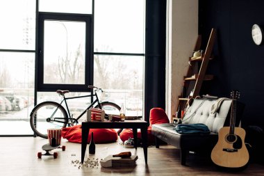 sehpa ile yiyecek ve içecek yakınındaki dağınık oturma odasında kanepe ve akustik gitar