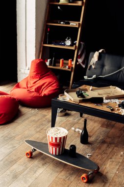 skateboard with popcorn box near coffee table in messy living room clipart