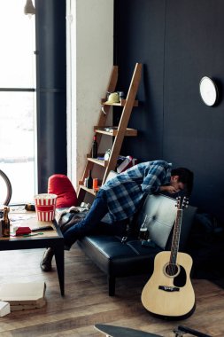 drunk man feeling nauseated after party in messy living room clipart