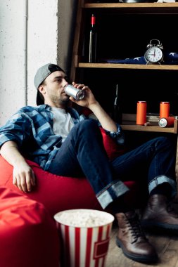 bira içmek olabilir ve evde fasulye çanta üzerinde oturan bir adam 